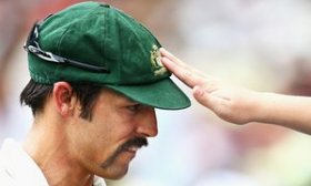 A fan reaches over the fence to touch former Australian paceman Mitchell Johnson’s baggy green.