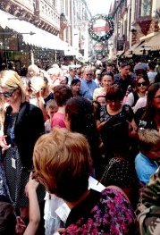 Fake foam snow falls in London Court,  crammed with people.