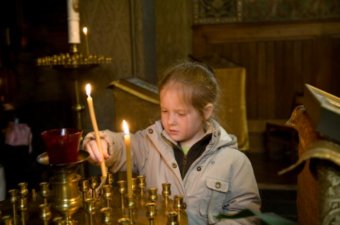 Little Girl light candles in an orthodox church