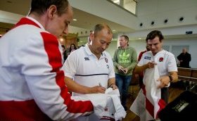 The England coach signs shirts for fans after arriving in Brisbane on Thursday
